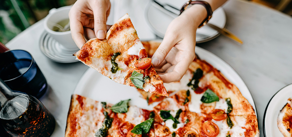 Two hands holding a slice of pizza.