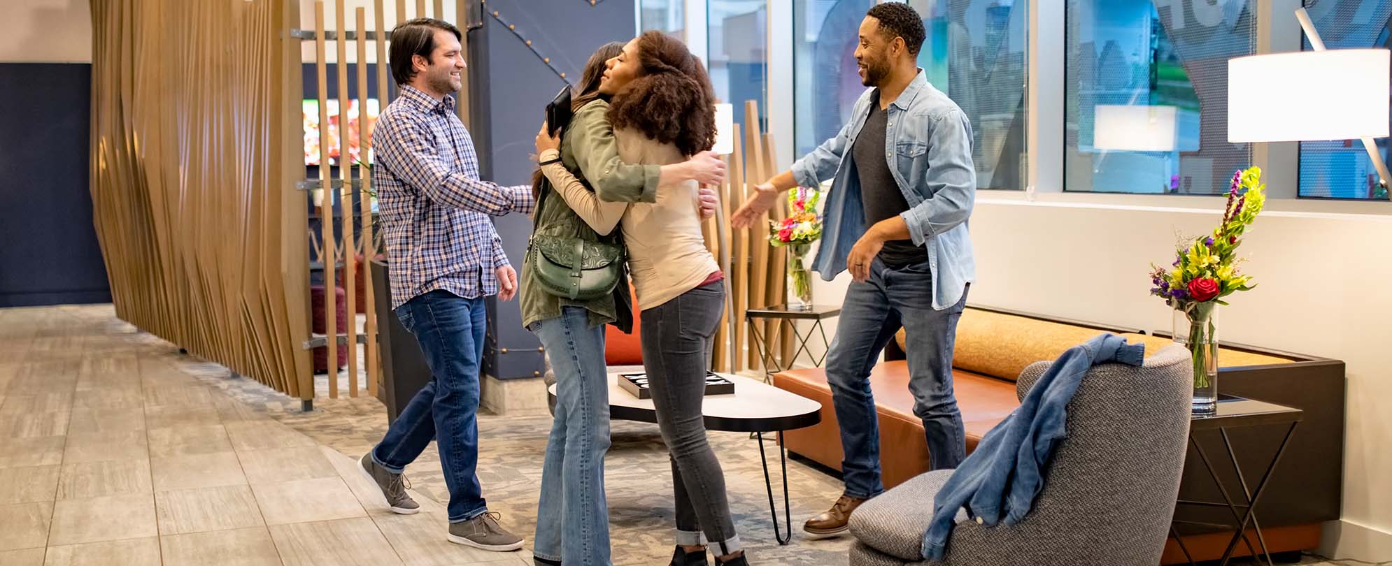 Two women greet each other in a hug and two men greet each other with handshakes in a WorldMark resort lobby.