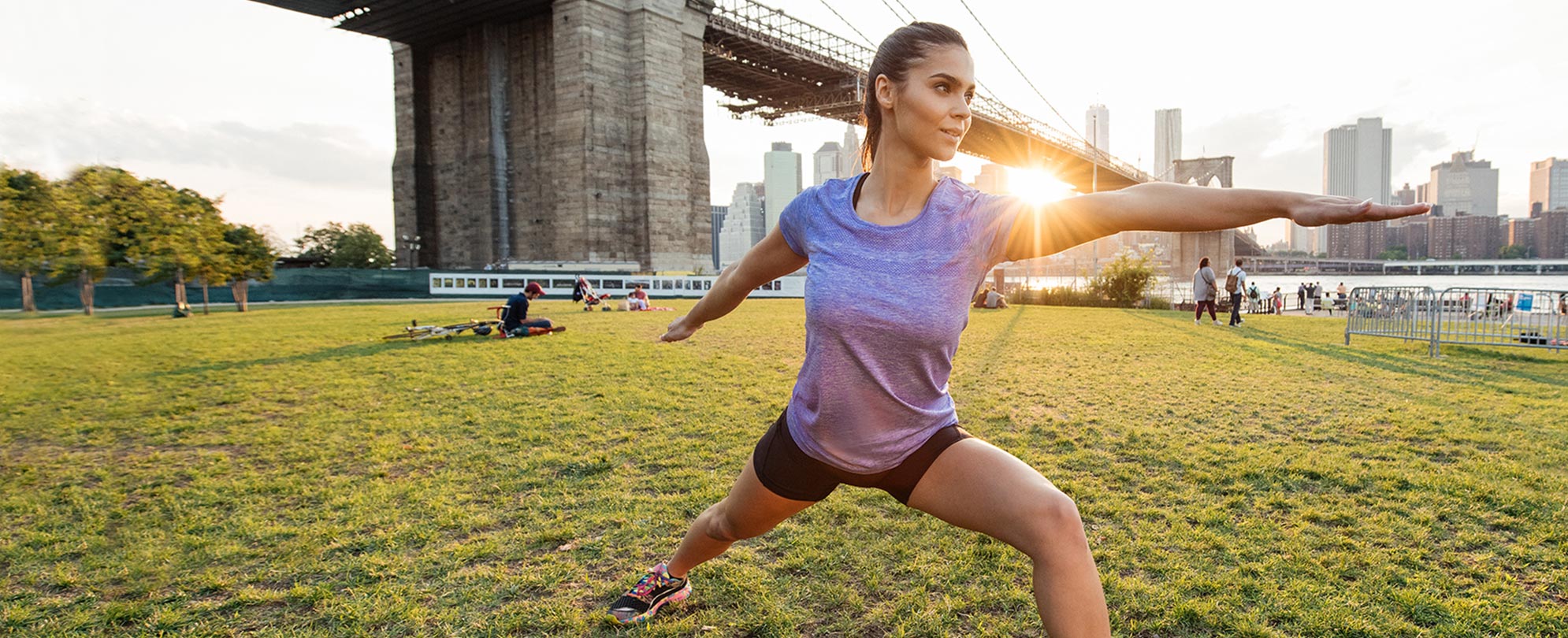 A woman lunging in a yoga pose outside on a grassy lawn