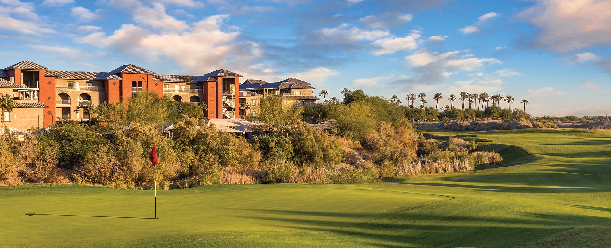 The green of a golf course, with Club Wyndham and WorldMark Indio timeshare resort in the distance.