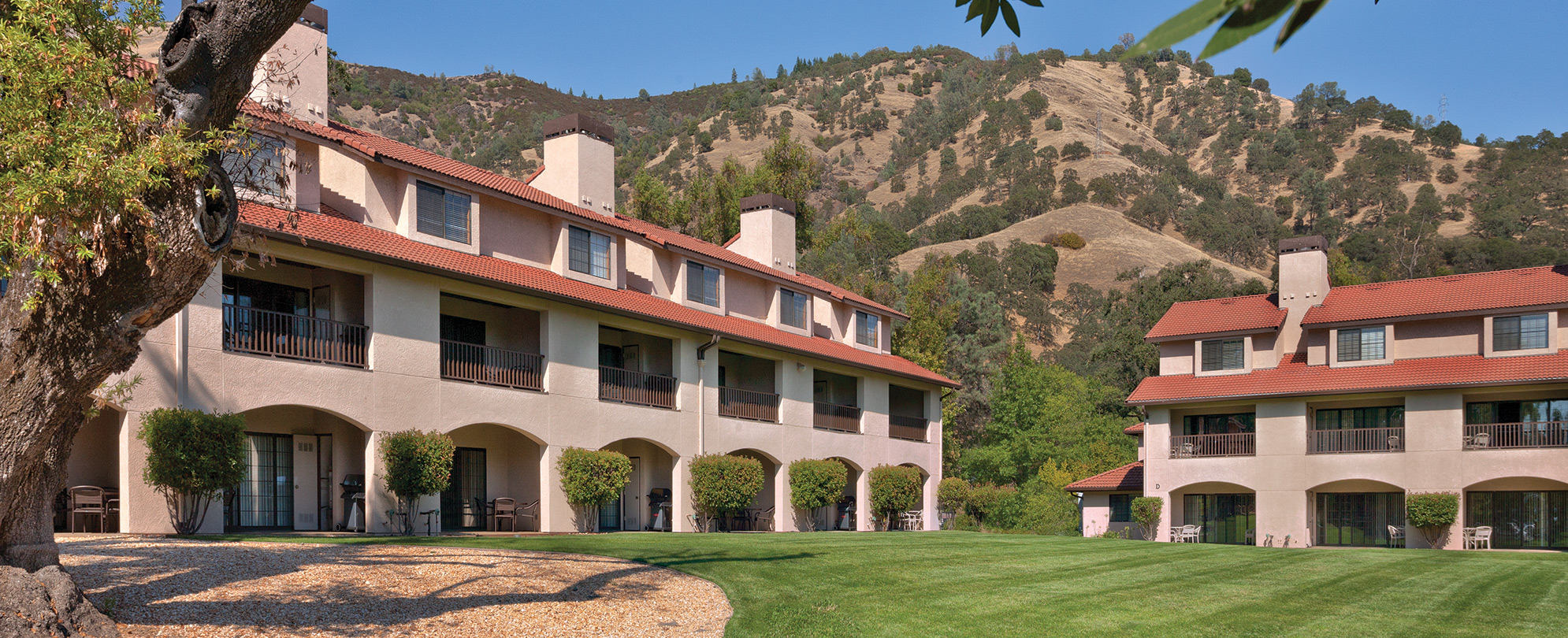 The exterior of a resort in front of a small mountain range at WorldMark Clear Lake.