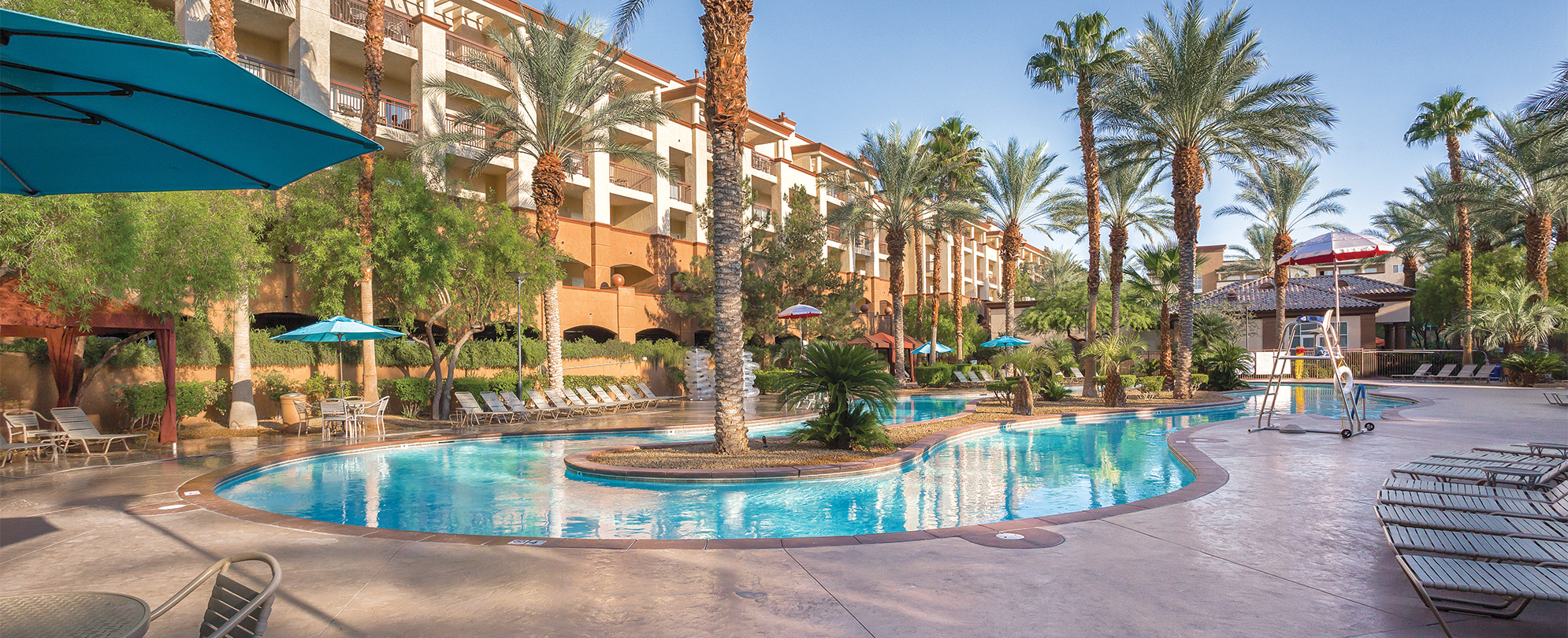 The outdoor pool and exterior of WorldMark Boulevard, surrounded by sun loungers and palm trees.