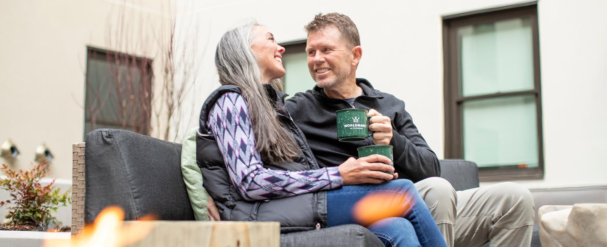 A couple looking at each other drinking coffee on the outdoor patio of a WorldMark by Wyndham resort.