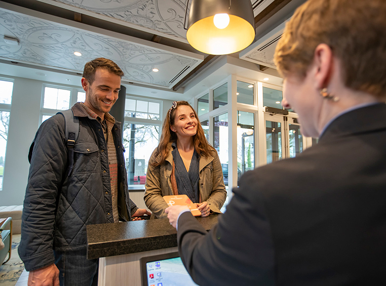 A couple checking in and being handed their room keys at the front desk of a WorldMark by Wyndham resort. 