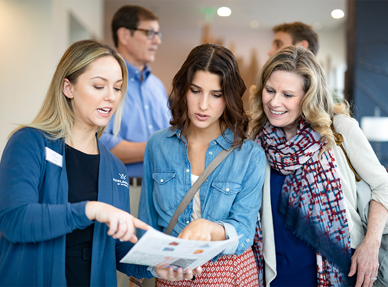 A WorldMark by Wyndham associate looks over paperwork with two women.