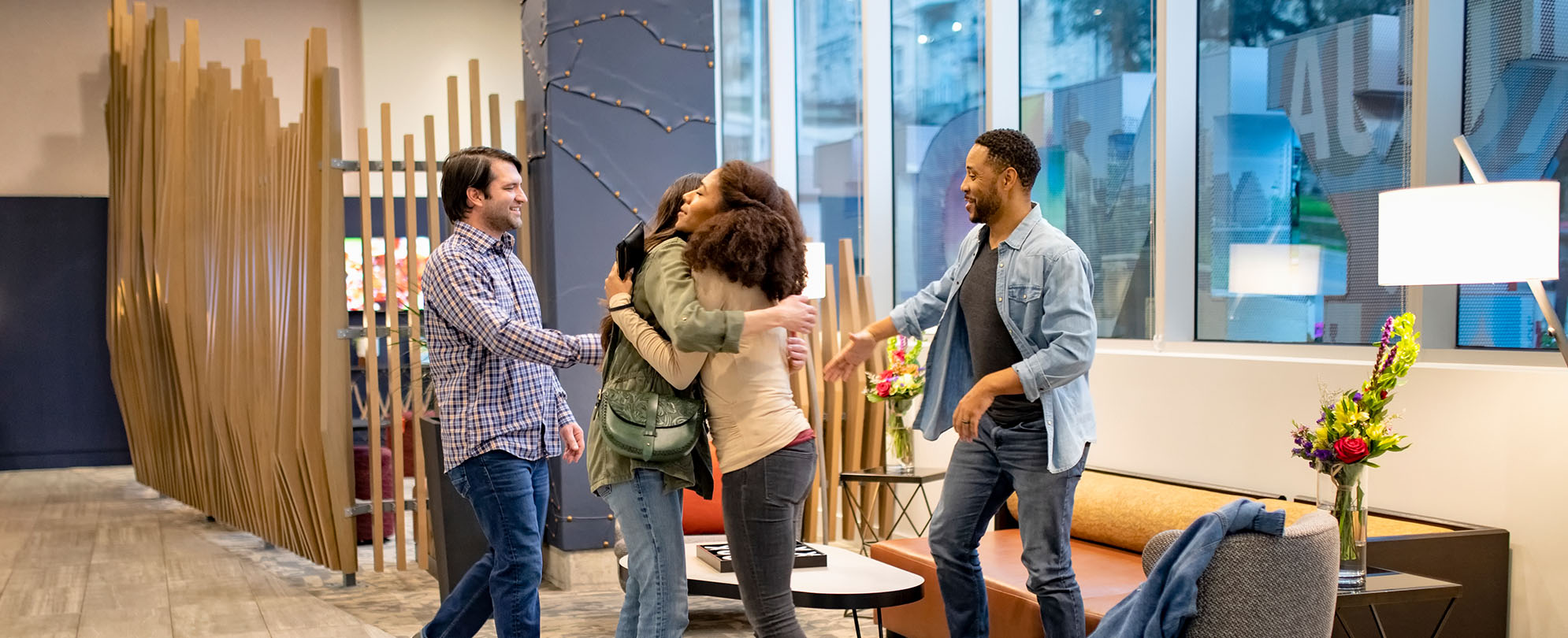 Two women greet each other in a hug and two men greet each other with handshakes in a WorldMark resort lobby.