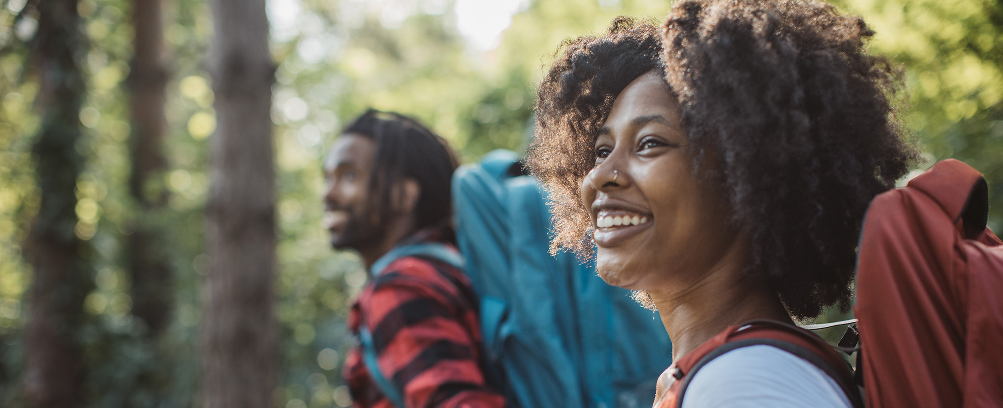 Close-up of a happy couple holding hands and hiking through woods.