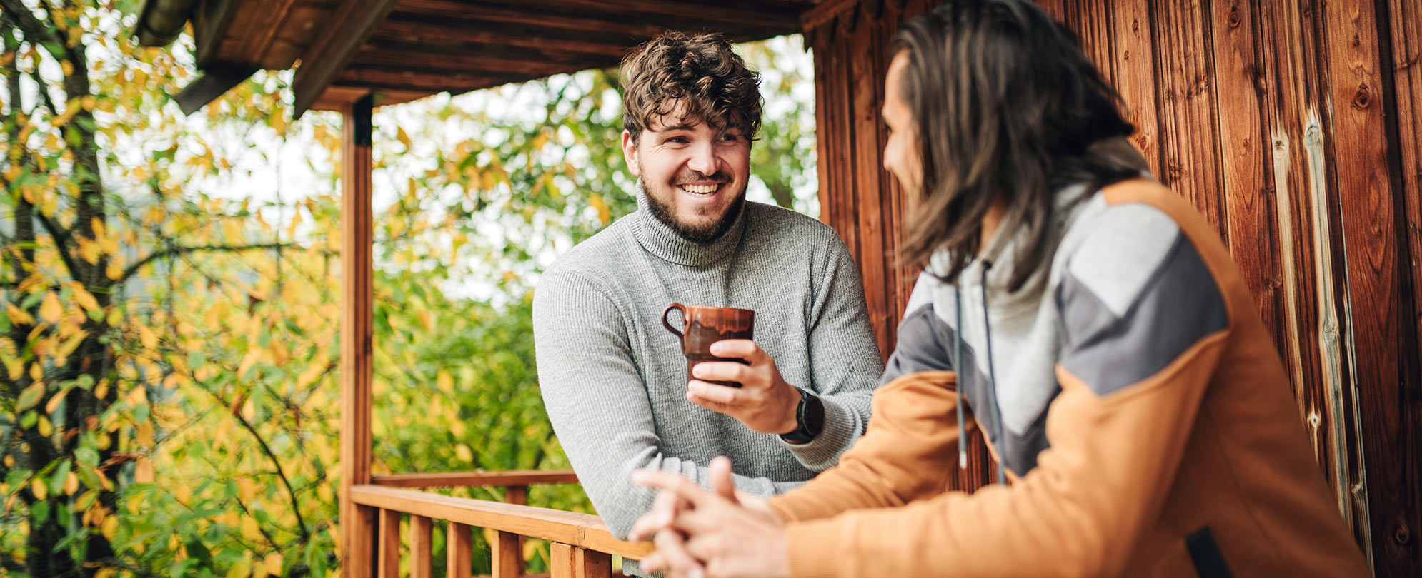 Two men standing by the balcony of a Club Pass resort cabin.